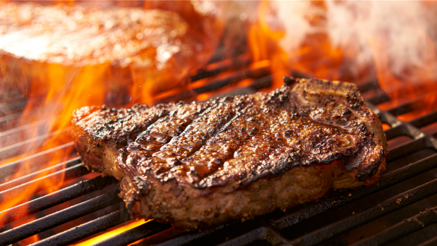Ein Steak liegt auf einem Grill über offenen Flammen