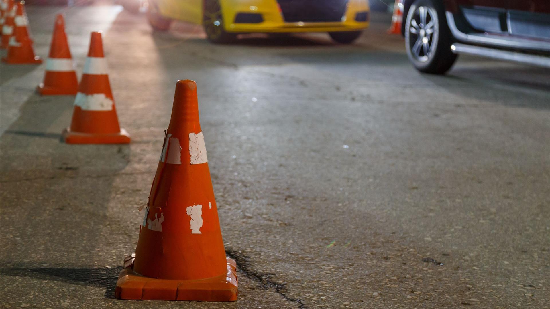 Verkehrskegel auf einer Strasse bei Nacht mit Autos im Hintergrund