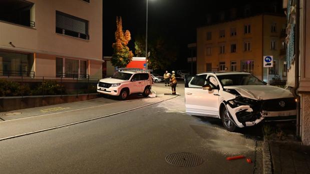 Nachts auf einer Straße stehen zwei beschädigte Autos nach einem Unfall, Einsatzkräfte sind vor Ort.