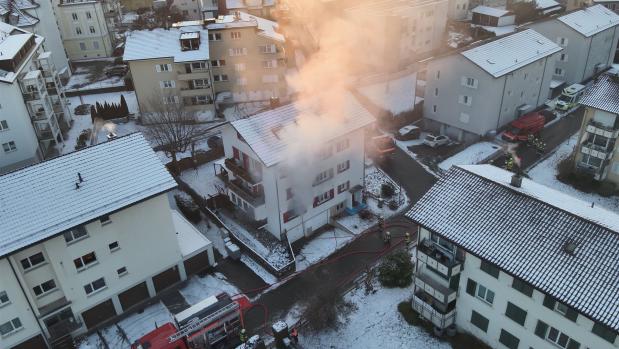Luftaufnahme eines verschneiten Wohnviertels mit Feuerwehreinsatz und aufsteigendem Rauch