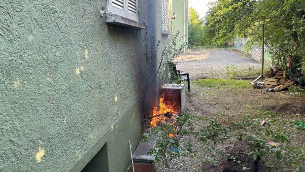 Ein kleiner Brand neben einer Hauswand im Gartenbereich
