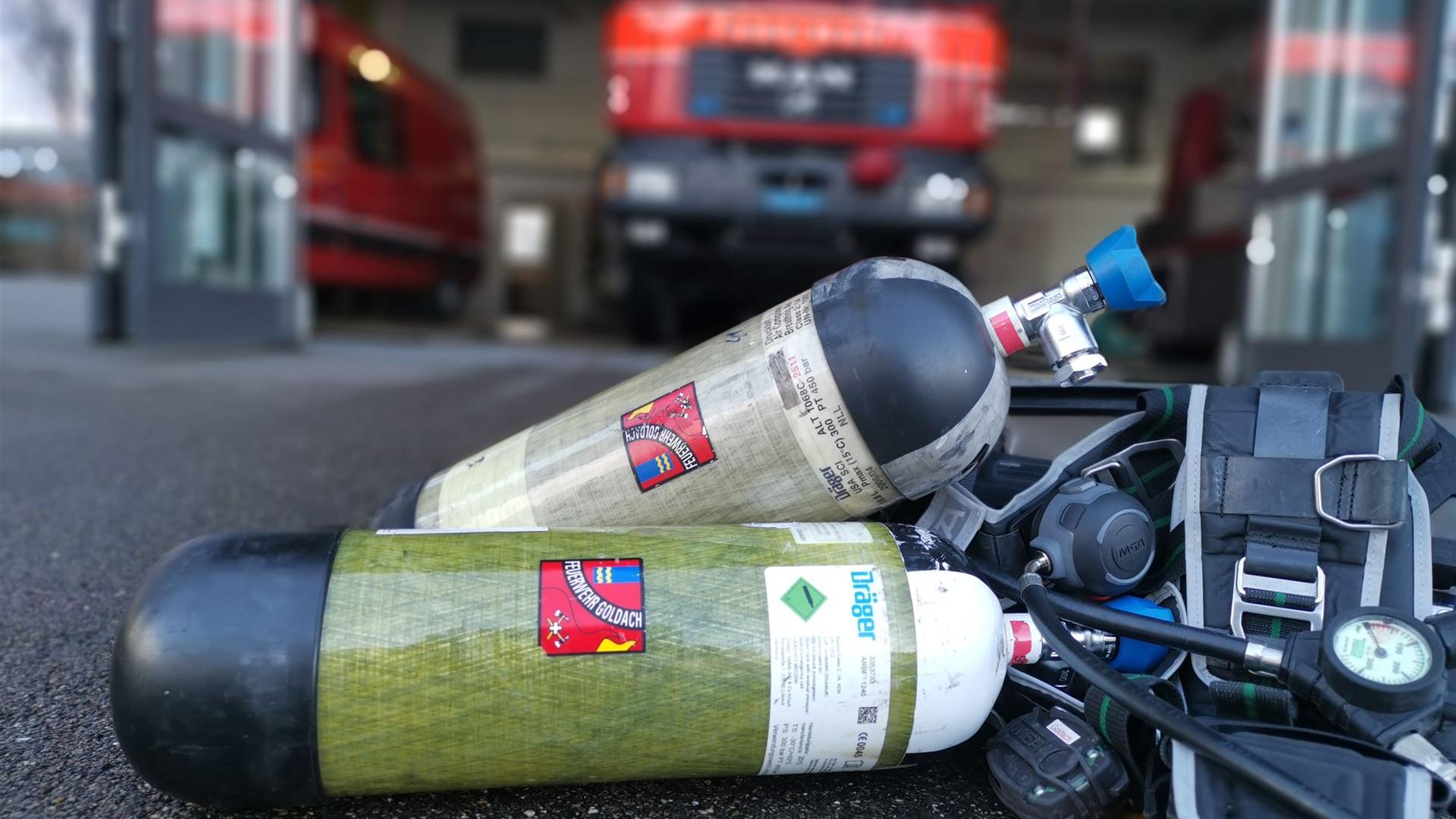 Atemschutzgeräte der Feuerwehr Goldach vor einem geöffneten Feuerwehrdepot mit Einsatzfahrzeug im Hintergrund