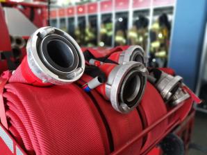 Zusammengerollte Feuerwehrschläuche mit Metallkupplungen vor Feuerwehrspinden